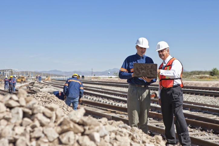 Two workers discuss track pans for railcar spill containment